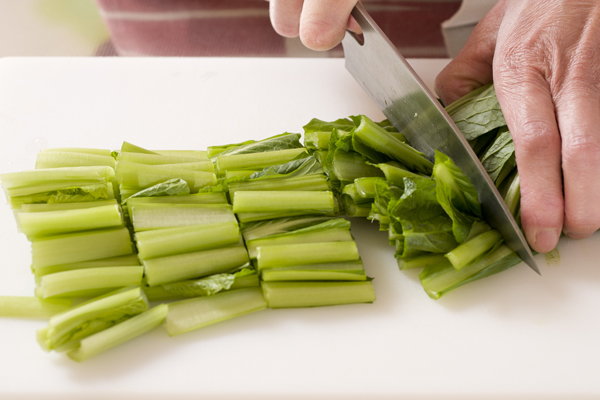 小松菜は根元を切り落として長さ3cm程度のざく切りにし、耐熱性のボウルに入れてラップをかけ、電子レンジで3分程度加熱する。加熱後、レンジから取り出してよく混ぜ、冷水で冷やしてから、水気を絞る。