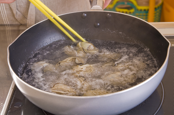 生カキはボウルに入れて流水を注ぎながら優しく洗い、塩少々を加えた熱湯で軽く湯通しする。