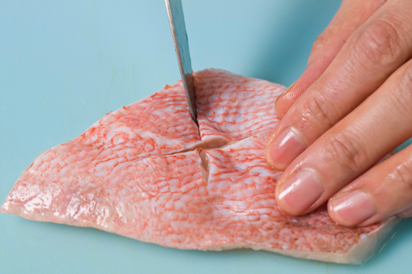 赤魚の切り身の皮に包丁で十文字に切れ目を入れる。ゴボウは皮を包丁でこそぎ、食べやすく切って水にさらし下茹でしておく。