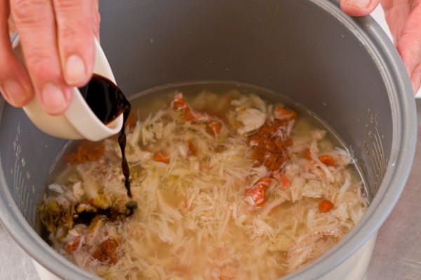 しょうゆ、酒、セイコガニのむき身とカニ味噌を入れ、ひと混ぜしてから、殻をのせて炊く。