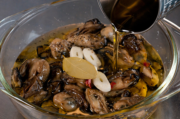 容器に2のカキ、1のニンニク、唐辛子、黒コショウ、ローリエを入れ、オリーブオイルを注ぎ入れ、軽く混ぜ合わせる。味を見て塩で調味する。
