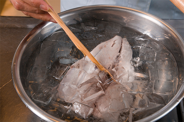 沸騰したお湯にカツオを数秒くぐらせる。表面の色が変わったらすぐ氷水に漬ける。