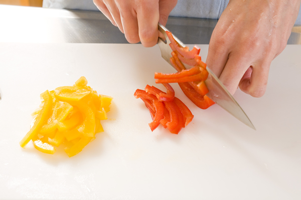 水菜は根元を切り落として長さ3㎝程度のザク切り、赤と黄のパプリカはヘタとタネを取り除いて横千切りにして混ぜ合わせ、器に敷き盛る。
