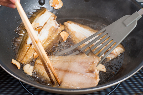 フライパンににんにくを塗りつけ、油を入れて熱し、魚に焼き色をつけて取り出す。