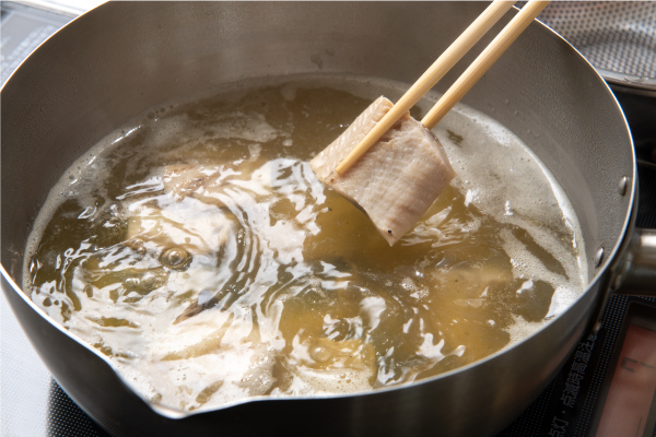 身欠きニシンは、頭と尾を切り落とし、4cm長さに切る。米のとぎ汁に漬ける（可能であれば1日）。腹骨を包丁でとる。番茶を入れたお湯で5分ほどゆでる。