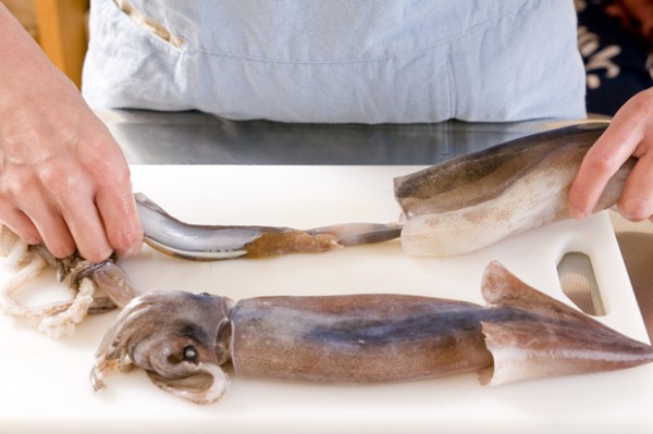 冷凍スルメイカは流水で解凍し、足と胴を分けて頭と内臓を取り除く。貝割れ菜は根元を切り落として、長さを半分に切る。