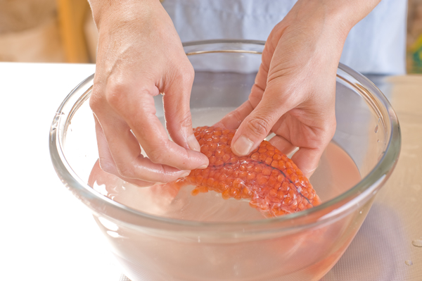 ボウルに水を入れて海水程度の濃さになるまで塩を加え、筋子を浸して汚れを取り除きながら洗う。