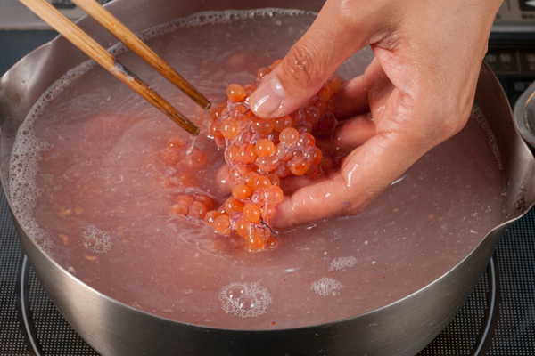 ボウルに50度位のお湯を用意して、筋子を入れ潰さないように指先でほぐす。