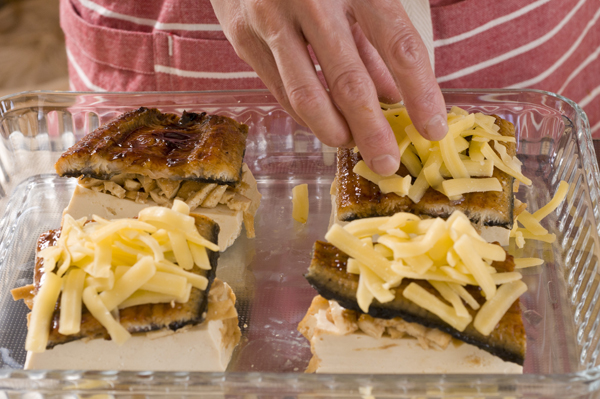 耐熱性の器に2の厚揚げの中の部分を間を空けて並べ、その上に蒲焼きのタレで和えた厚揚げの周りの部分を等分に乗せ、それを挟むようにして1のうなぎの蒲焼きを乗せる。更にピザ用チーズを乗せ、電子レンジで5分程度加熱してチーズがとろけたら器に盛り、万能ネギの小口切りを散らす。